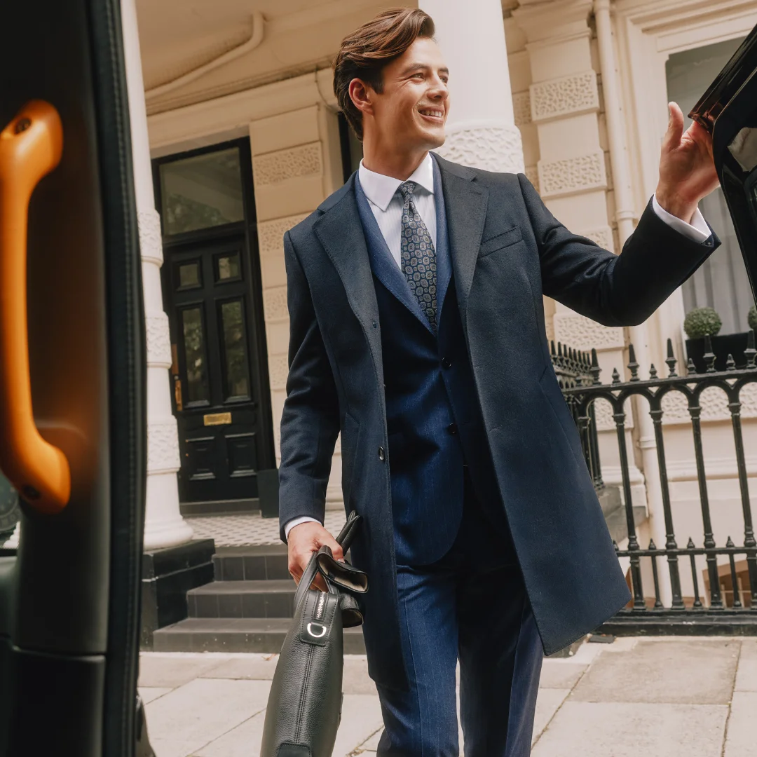 Man wearing suit getting into a London Taxi