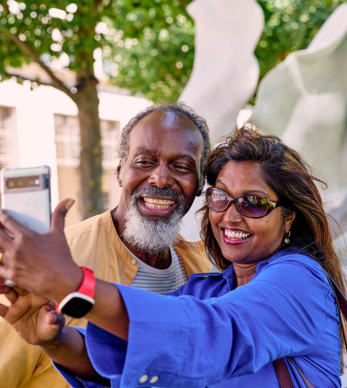 Couple taking a selfie in front of an Helaine Blumenfled sculpture at Canary Wharf