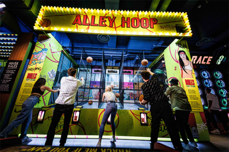 People playing fairground games indoors at Fairgame