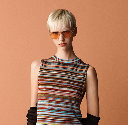 Woman wearing a multi coloured stripy top and red sunglasses
