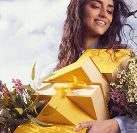 Woman carrying lots of yellow gift boxes