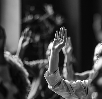 Black and white image of people raising their hands to ask questions