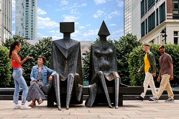 People near the sculpture, Lynn Chadwick: Couple on Seat, in Cabot Square