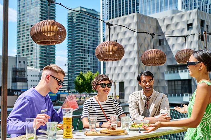 A group of friends enjoying food and drinks in front of an urban vista