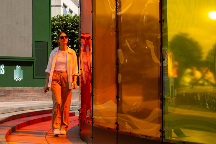 A lady walking besides colorful reflective glass windows