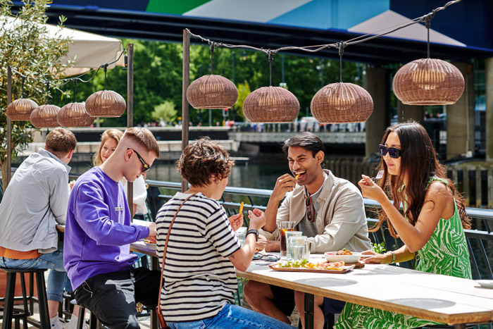 Friends having delicious meals while overlooking Eden Dock at waterfront restaurant