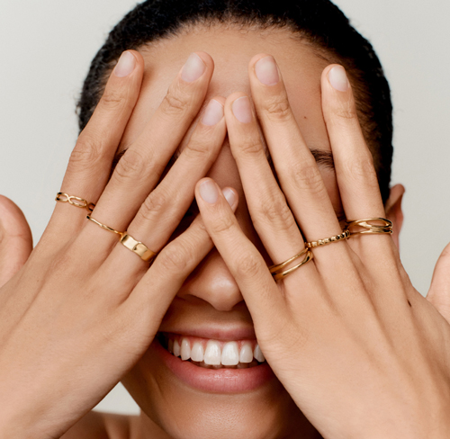 A happy women showing off her many rings she's wearing