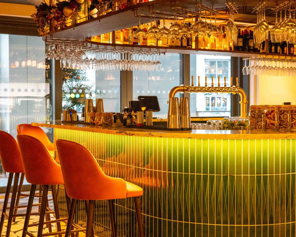 a bar with green tiles and orange chairs