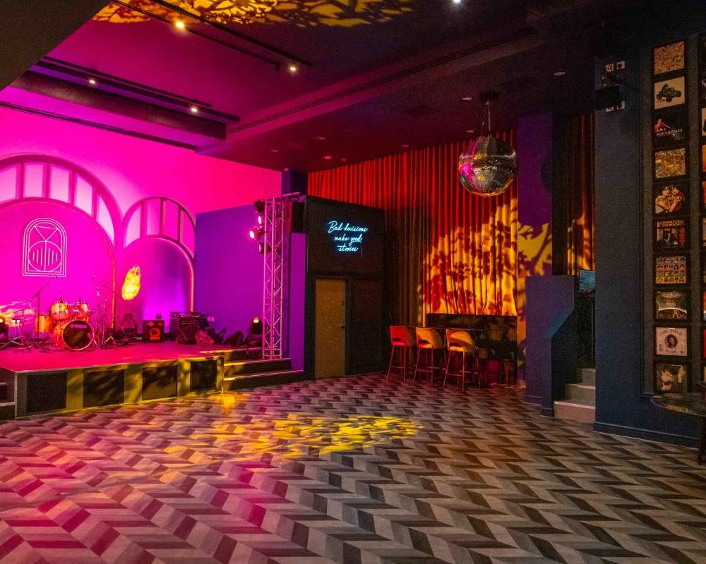 dance floor in a bar with pink lights and drum kit on stage