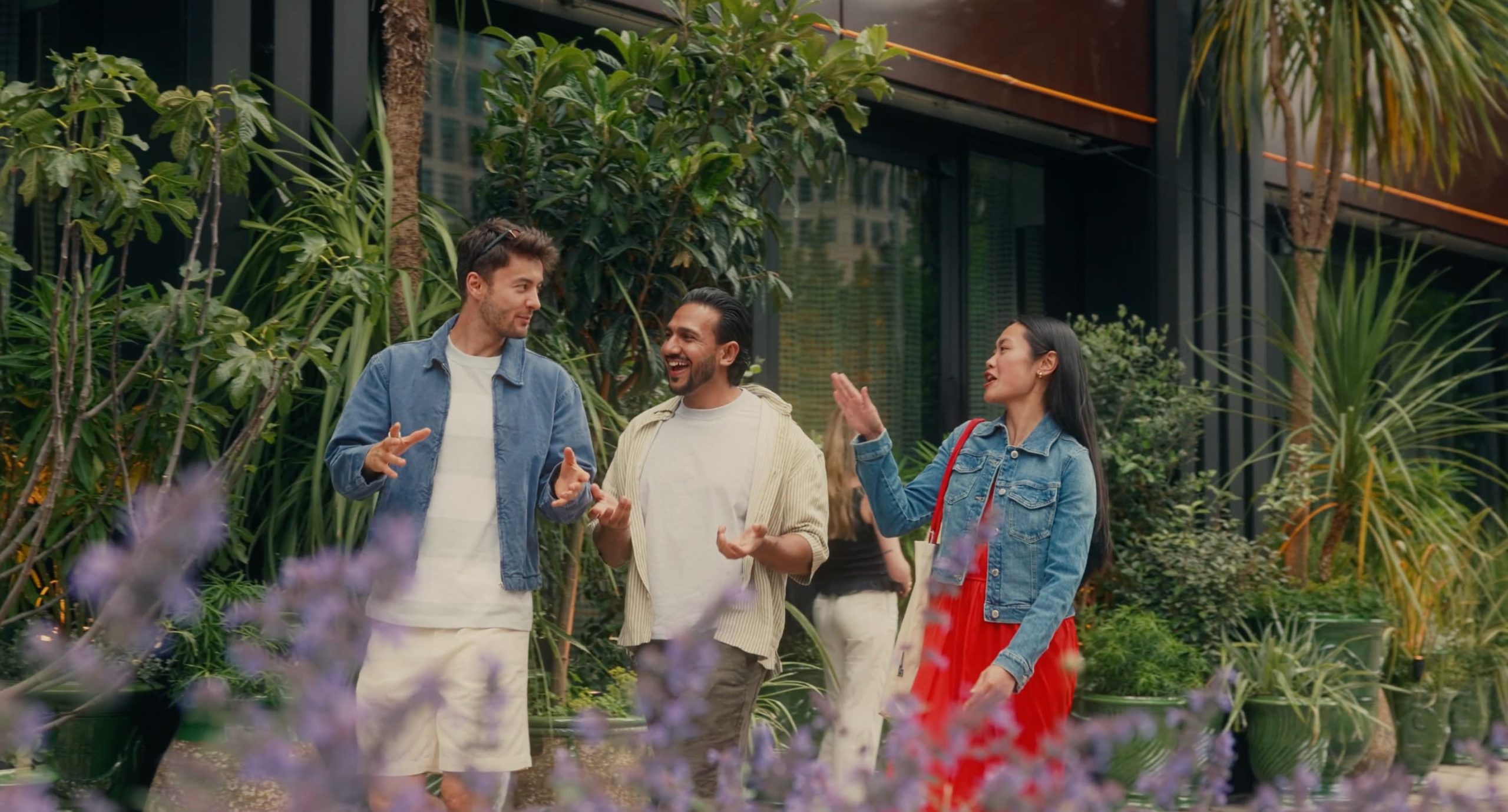 Three people walking around buildings and greenery