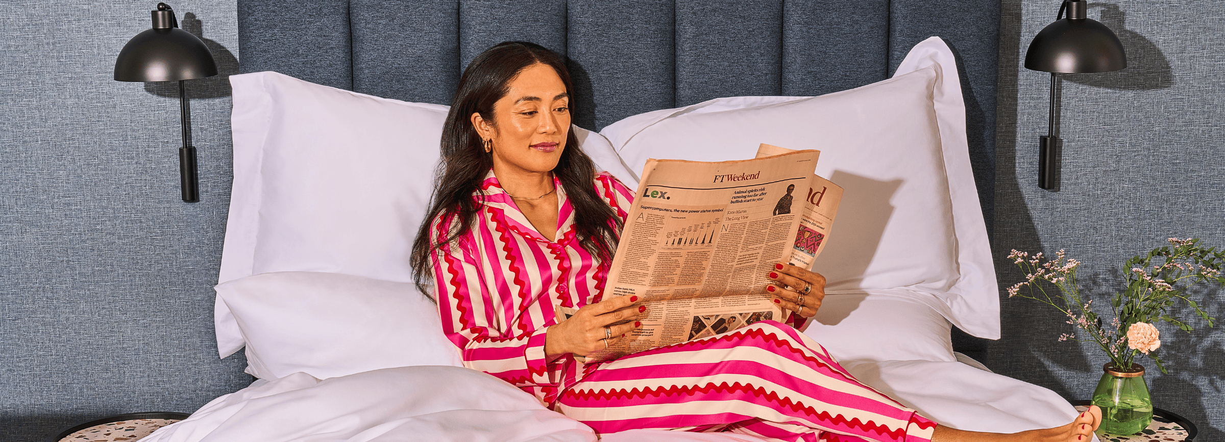 Lady lying on bed reading newspaper