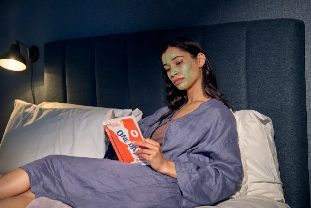 women with green facemask reading book