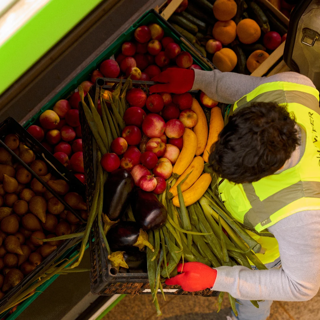 Man in hi-vis carrying vegetables and fruit