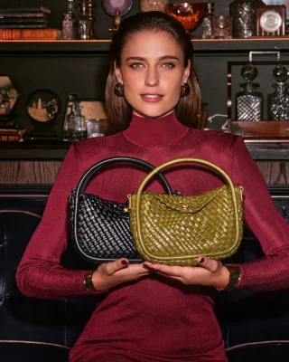 Women holding a green and black handbag