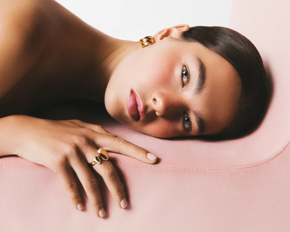 girl lying on side with gold ring and earrings