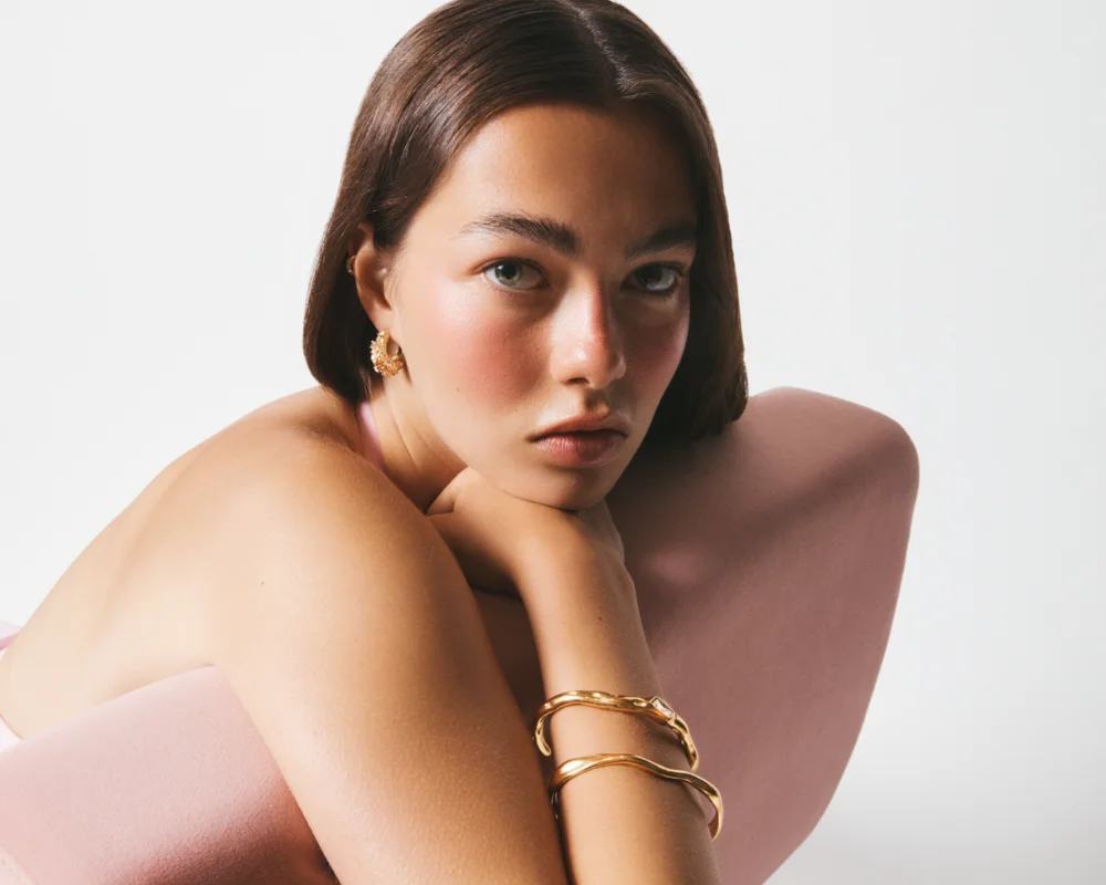 women with hand on chin and gold bangles