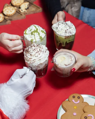 Father christmas hand and other peoples holding hot chocolates