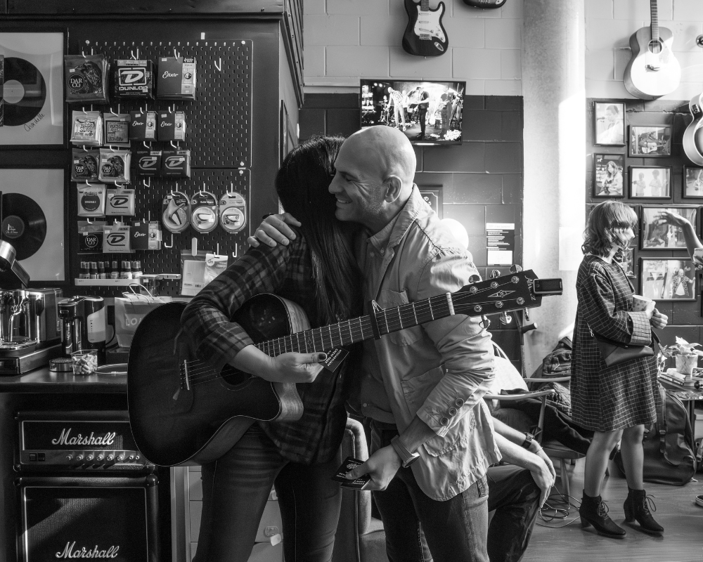 men hugging whilst holding guitar